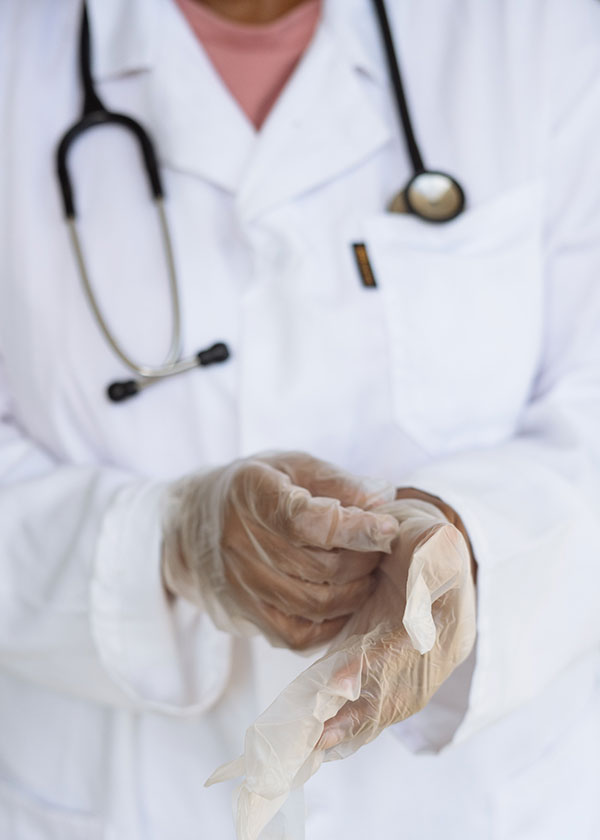 human-subject-main-v1.jpg Person in white lab coat taking off rubber gloves