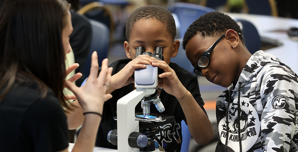 research-outreach-v1.png Two kids looking through a scope during one of the research events on campus.