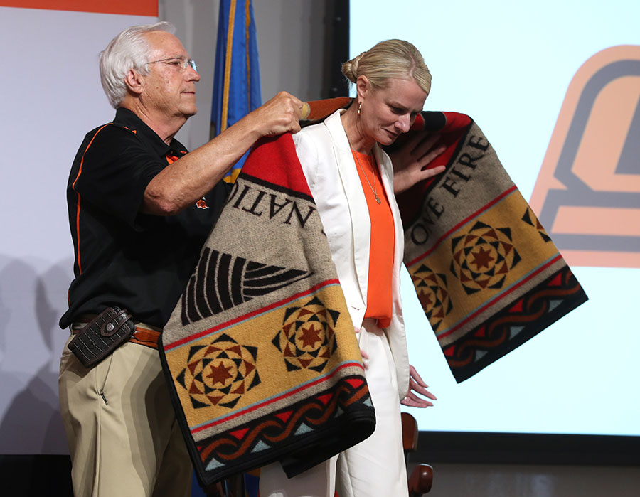 Dr. Kayse Shrum (right) accepts a “one fire” blanket from previous Cherokee Nation Principal Chief Bill John Baker during a reception for Dr. Kayse Shrum and Dr. William Pettit at the Oklahoma State University Center for Health Sciences in Tulsa, Oklahoma. Dr. Kayse Shrum (right) accepts a “one fire” blanket from previous Cherokee Nation Principal Chief Bill John Baker during a reception for Dr. Kayse Shrum and Dr. William Pettit at the Oklahoma State University Center for Health Sciences in Tulsa, Oklahoma.