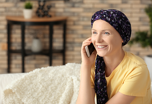 Woman wearing a head wrap speaking on the phone smiling.