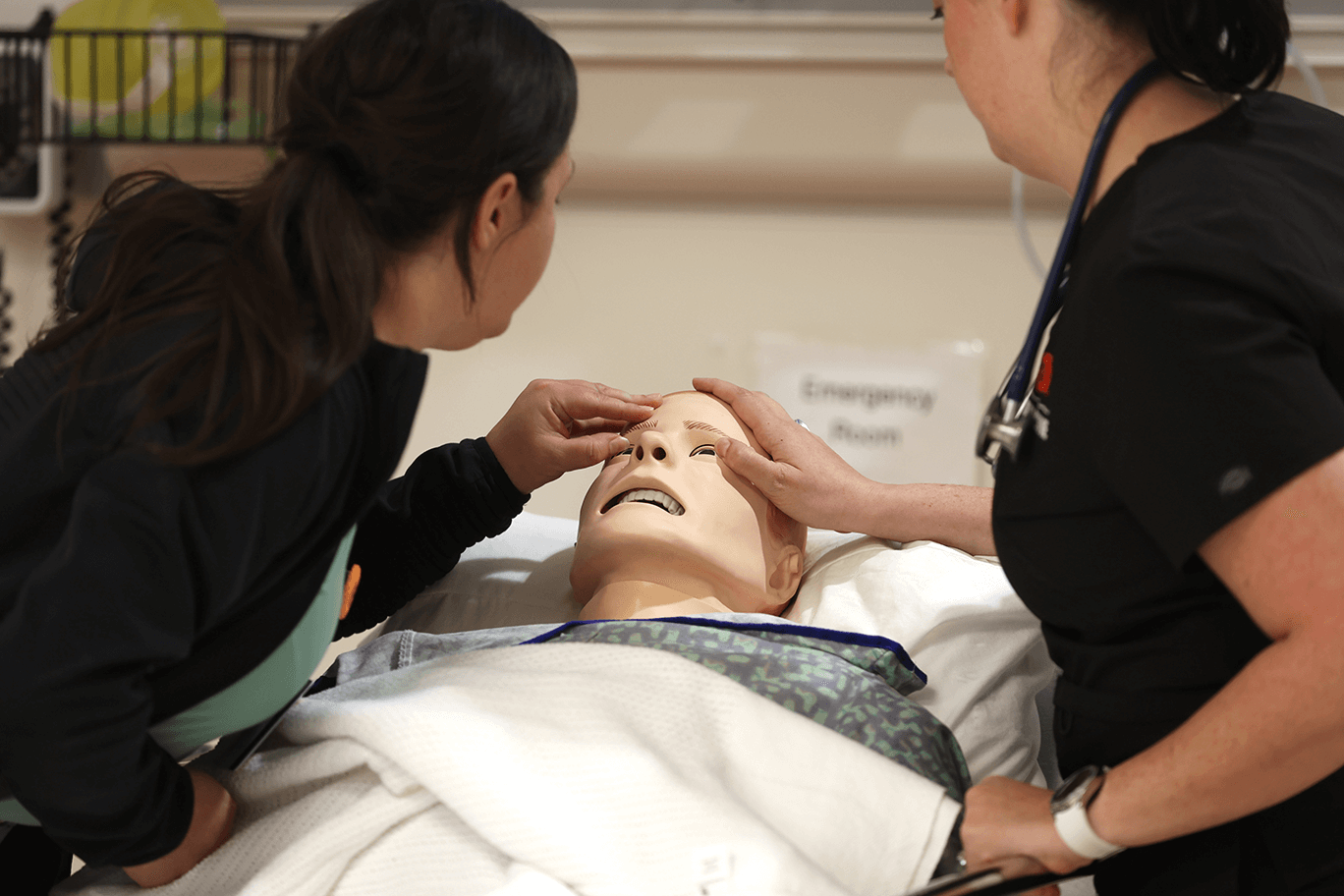 Simulation Club members checking a medical mannequin for a fever.